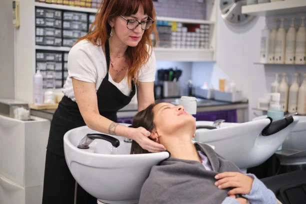 Stylish hairdresser washing the hair of a beauty chinese client in a salon SEO Services For Salon Business